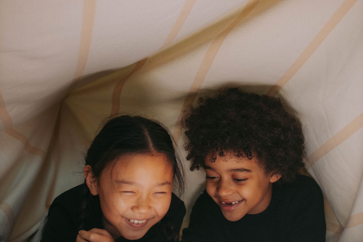 A child resting snugly under a weighted blanket on a soft floor mat