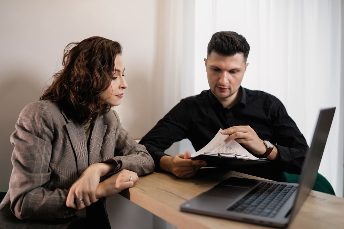 A parent reading an NDIS plan at a table with a notebook and laptop