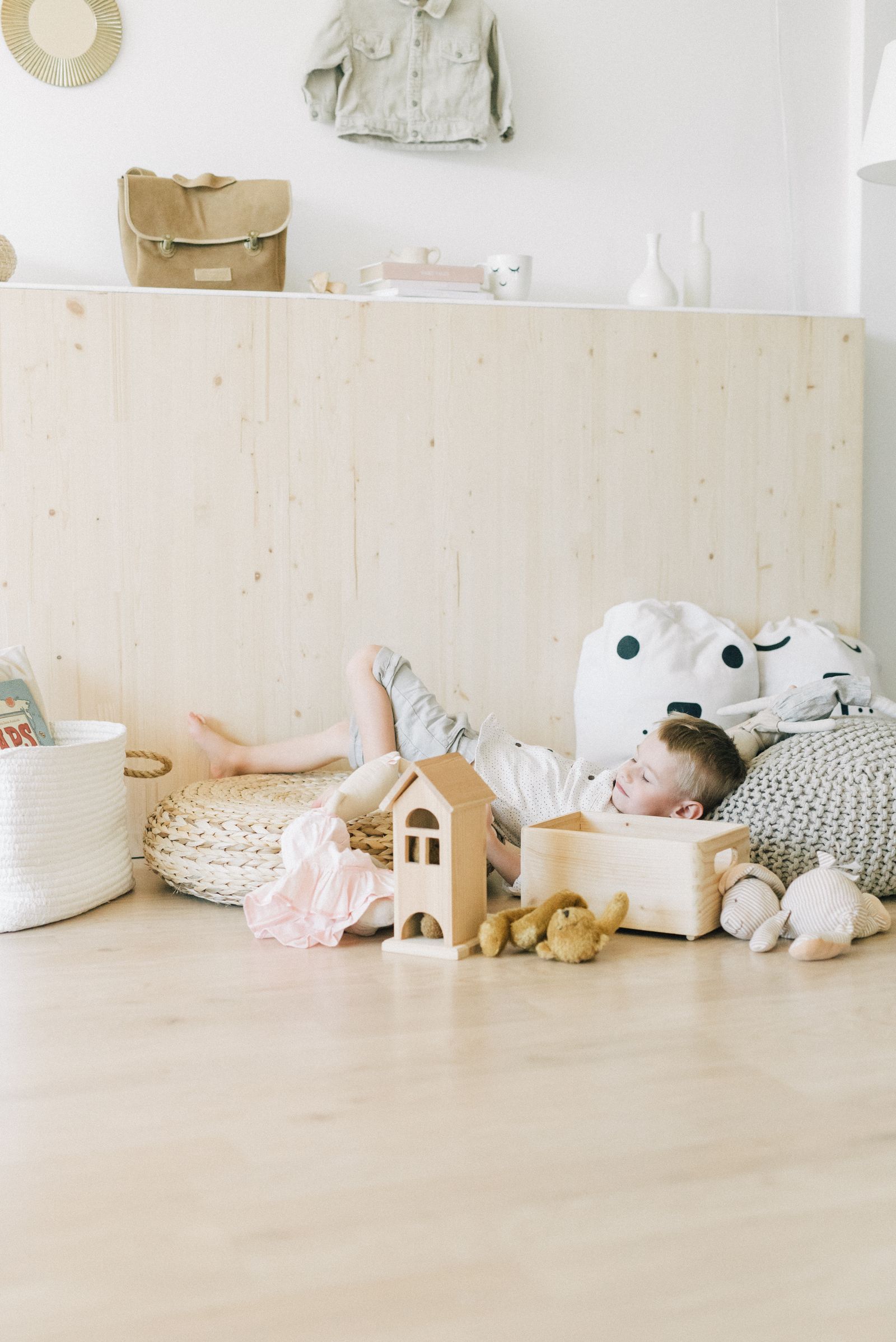 A young child resting calmly on a soft padded floor mat in a warm, light-filled room